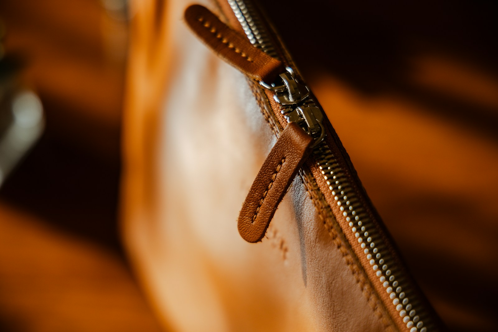 A close-up of a tan leather zip and pull, representing the crossbody category.