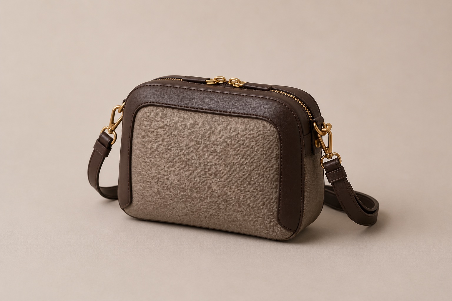 The Lumen crossbody in taupe performance textile with a dark-chocolate leather frame and brass hardware, strap attached.