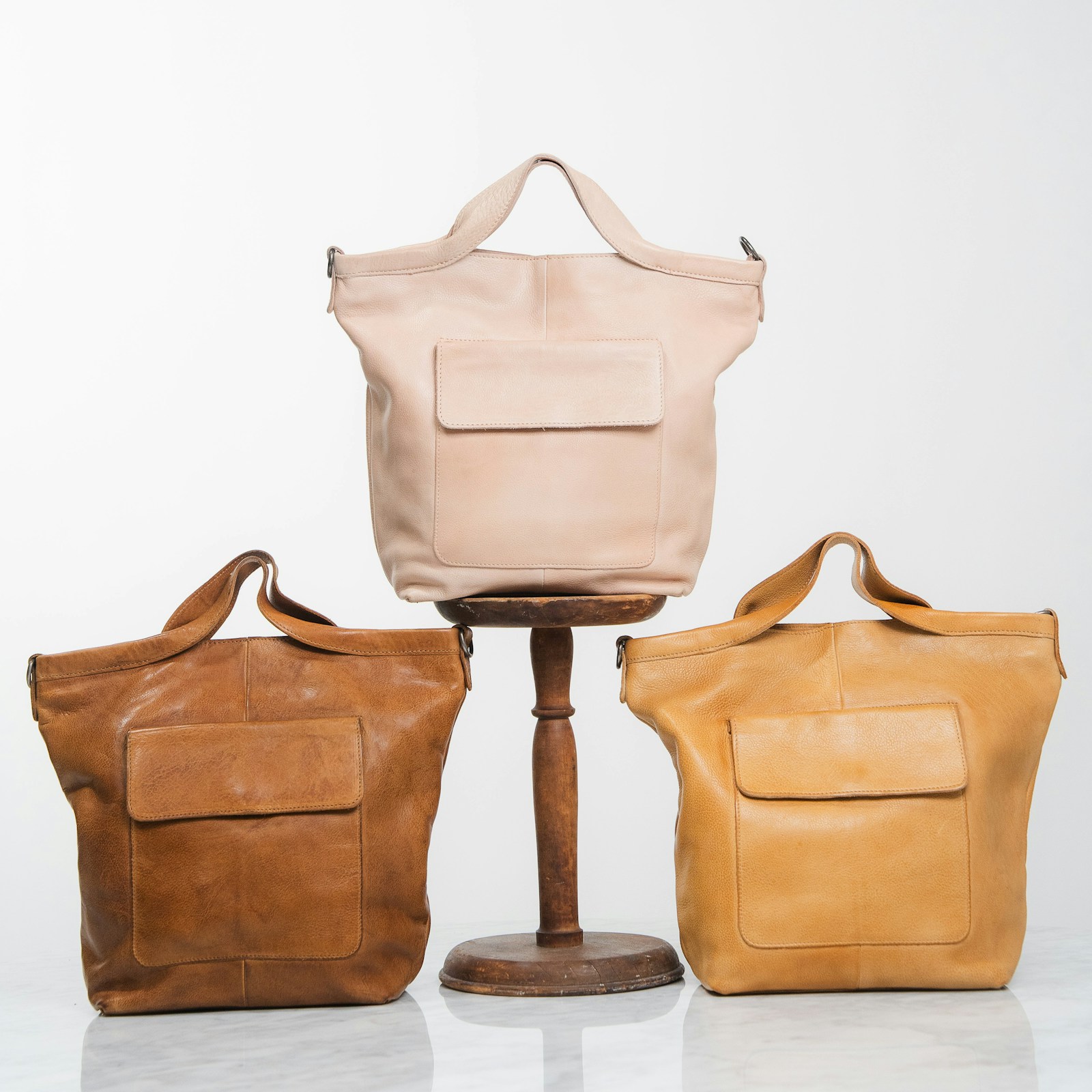Three leather totes in tan and cream tones, representing the tote category.